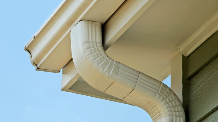 Close-up of a white gutter system on a house with a blue sky background